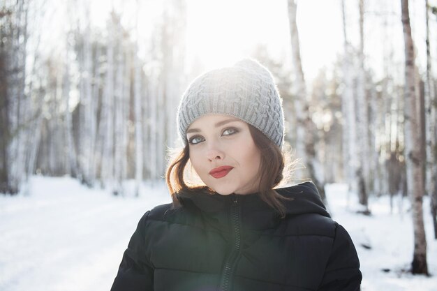 Bella ragazza in una foresta bianca d'inverno