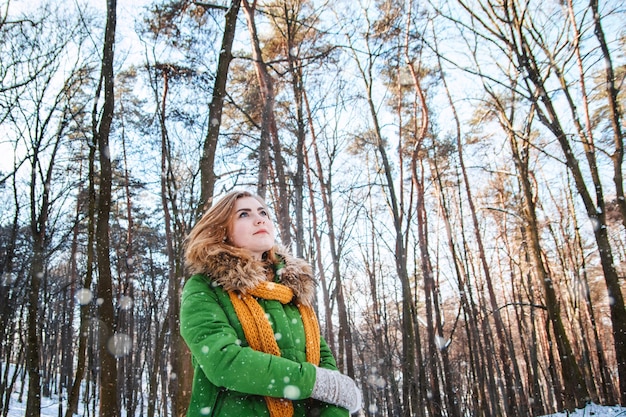 Bella ragazza in una giacca invernale e guanti su uno sfondo di foresta