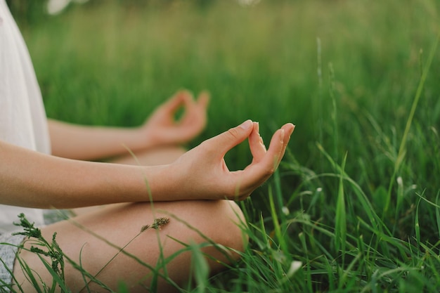 Bella ragazza in una maglietta bianca che fa yoga in un bellissimo campo. Uno stile di vita sano