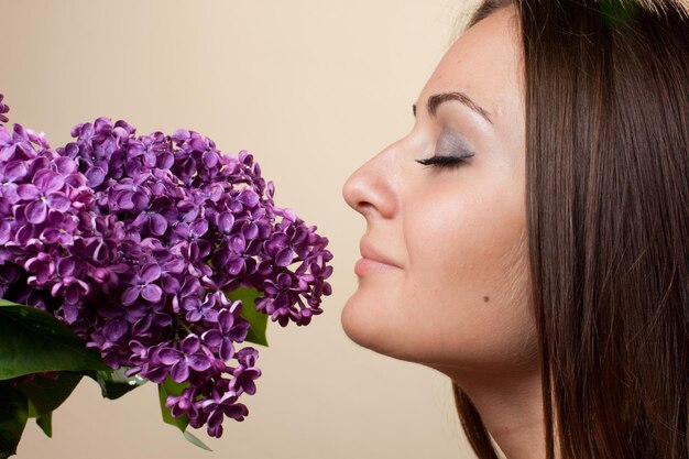 Bella ragazza indossata in abito nero con un bouquet di lillà