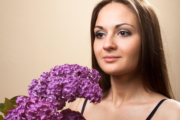 Bella ragazza indossata in abito nero con un bouquet di lillà