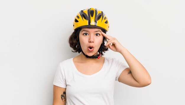 Bella ragazza ispanica che sembra sorpresa nel realizzare una nuova idea di pensiero o concetto di bici