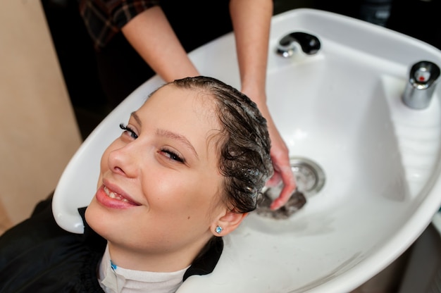 Bella ragazza lava i capelli in salone