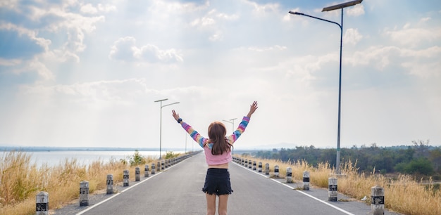 Bella ragazza mani in alto e guardando lontano per strada, rilassarsi e felice.