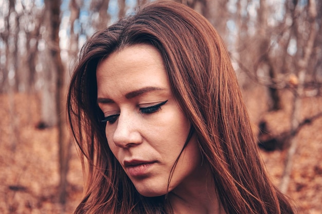 Bella ragazza nel bosco vicino agli alberi