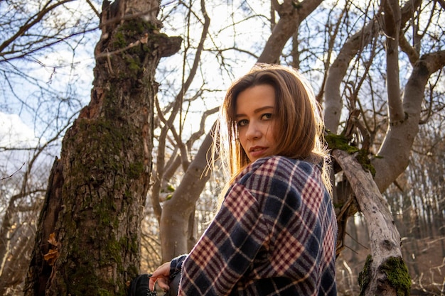 Bella ragazza nel bosco vicino agli alberi