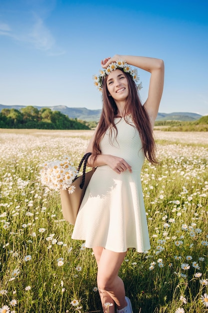 Bella ragazza nel campo della margherita Tramonto estivo felice giovane signora e concetto di armonia della natura primaverile spensierata donna bruna felice con sani capelli ondulati divertendosi all'aperto nella natura