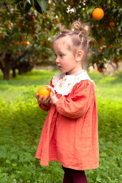 Bella ragazza nel giardino degli aranci e arance mature sui rami degli alberi