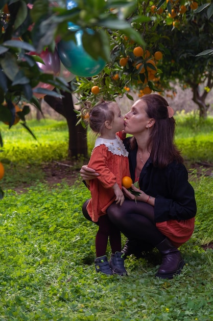 Bella ragazza nel giardino degli aranci e arance mature sui rami degli alberi