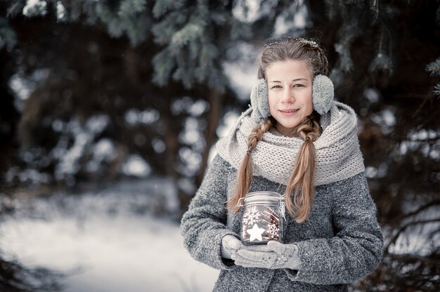 Bella ragazza nella decorazione della tenuta della foresta di inverno