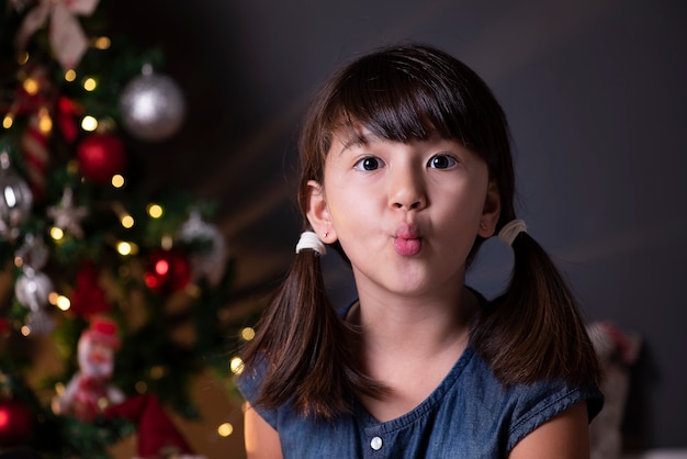 Bella ragazza nella decorazione di Natale che soffia bacio