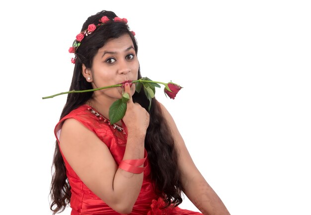 Bella ragazza o donna che tiene e che posa con il fiore della rosa rossa su bianco