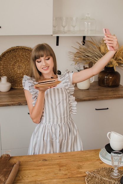 Bella ragazza pasticcere o casalinga fa selfie con la torta Il concetto di un blog culinario