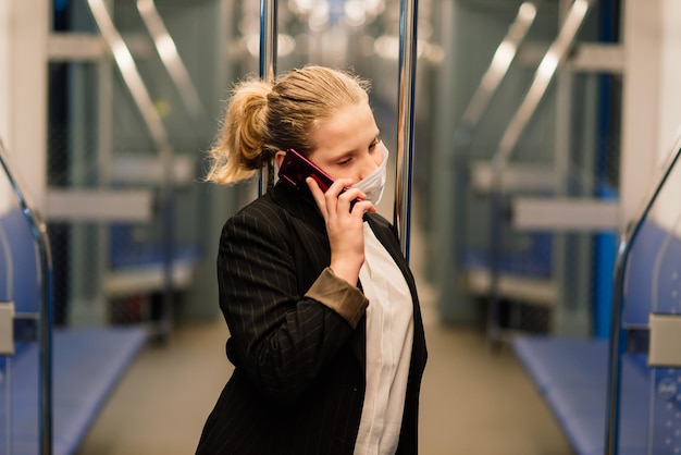 Bella ragazza piuttosto preoccupata che indossa maschera e cuffie in autobus, treno o metropolitana per andare a scuola