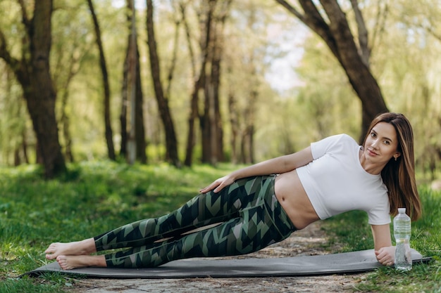 Bella ragazza plus size che fa yoga in natura in una soleggiata giornata estiva Sport positivi per il corpo per le donne