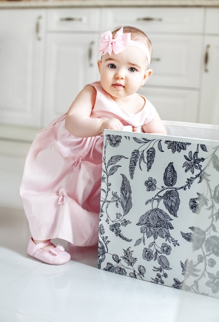 Bella ragazza prende i giocattoli dalla scatola. Vestito rosa.