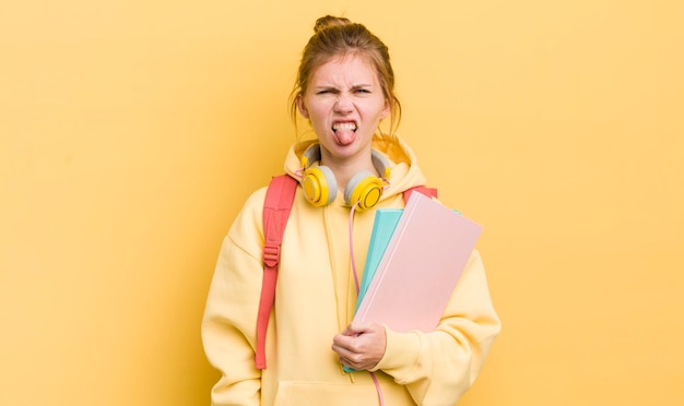 Bella ragazza rossa che si sente disgustata e irritata e con la lingua fuori il concetto di studente