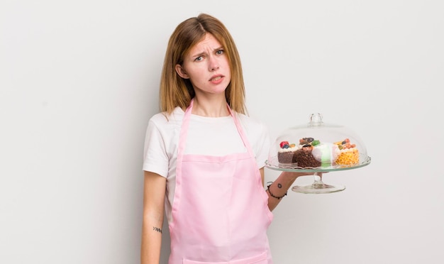 Bella ragazza rossa che si sente perplessa e confusa concetto di torte fatte in casa