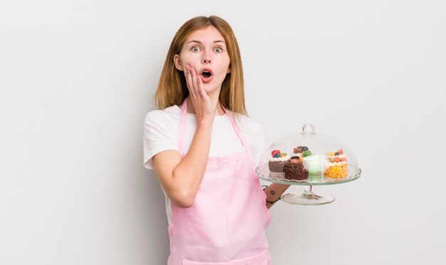 Bella ragazza rossa che si sente scioccata e spaventata concetto di torte fatte in casa