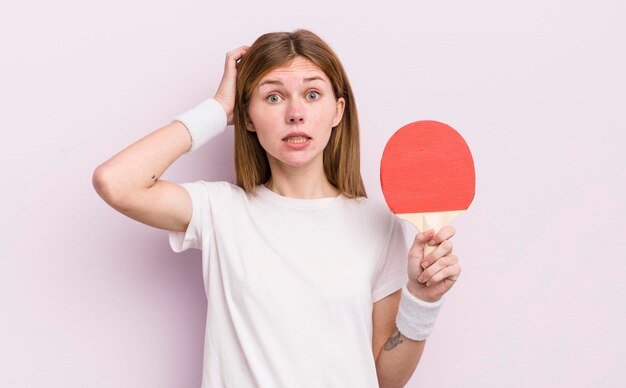 Bella ragazza rossa che si sente stressata ansiosa o spaventata con le mani sul concetto di ping pong testa