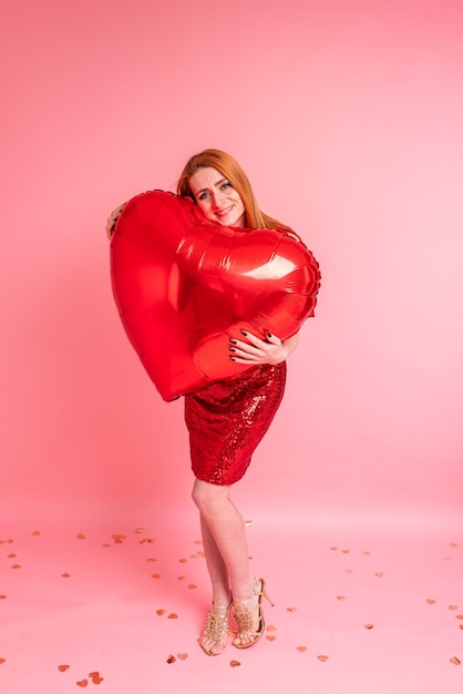 Bella ragazza rossa con baloon cuore rosso in posa Buon San Valentino concetto