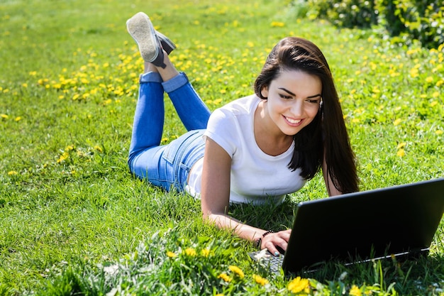 Bella ragazza seduta nel parco con un computer portatile