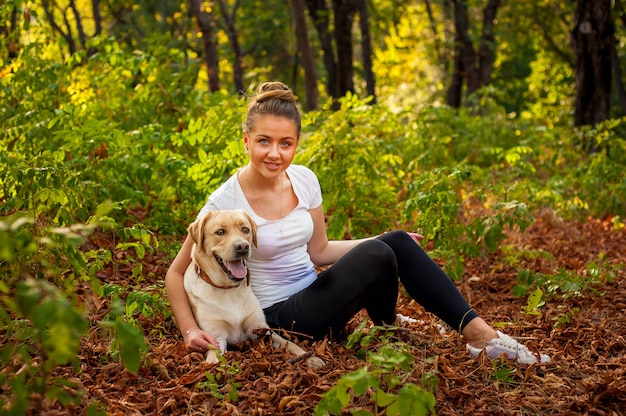 bella ragazza seduta nella foresta con un cane e accarezzare il suo amato animale domestico