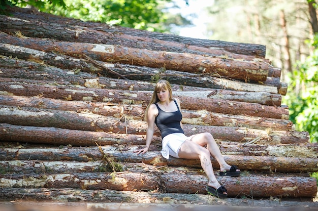 Bella ragazza seduta su tronchi tagliati nella foresta