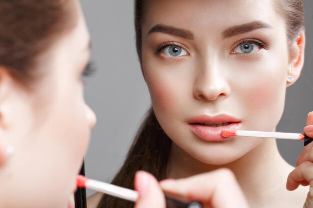 Bella ragazza si fa un trucco nello specchio Bellezza viso Foto scattata in studio