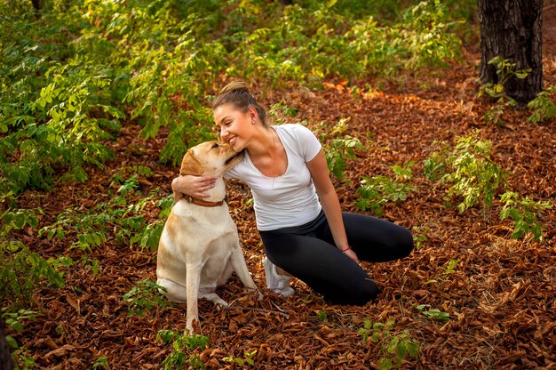 bella ragazza si siede in una foresta con un cane e bacia il suo amato animale domestico