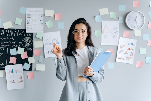 Bella ragazza sicura di affari con i documenti nelle mani sull'area di lavoro