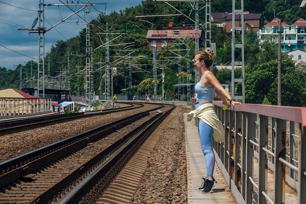 bella ragazza snella atleta si alza e riposa dopo il fitness in natura sul ponte ferroviario