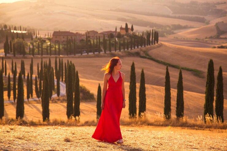 Foto bella ragazza snella in un vestito rosso al tramonto in toscana, italia