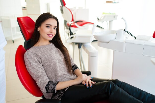 Bella ragazza sorride sulla poltrona del dentista.