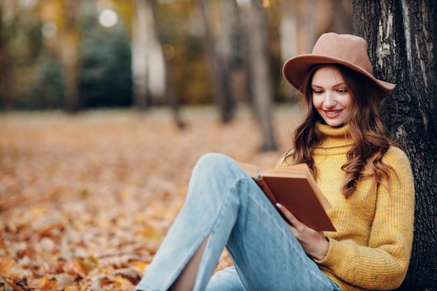 Bella ragazza sorridente al parco autunnale volante caduta foglie gialle del fogliame