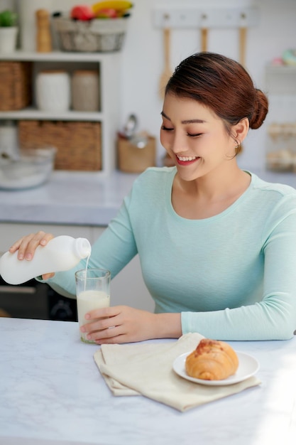 Bella ragazza sorridente che mangia una gustosa colazione sana mentre era seduto al tavolo della cucina