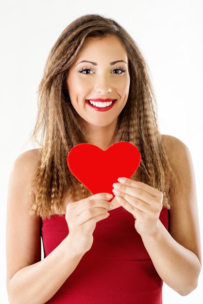 Bella ragazza sorridente che tiene un cuore rosso. Guardando la fotocamera.