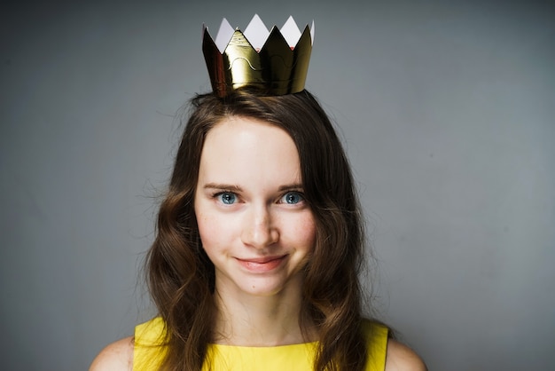 Bella ragazza sorridente in abito giallo, con una corona d'oro in testa, in attesa della Giornata mondiale della donna