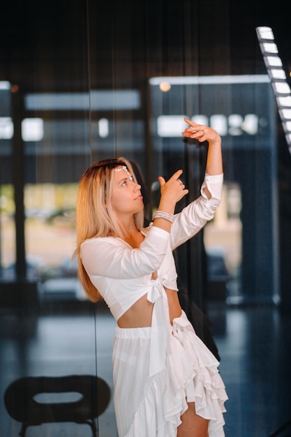 Bella ragazza sorridente in un vestito bianco che balla in palestra