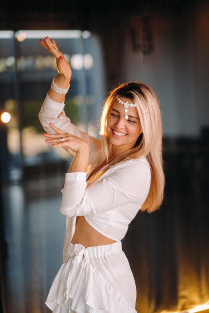 Bella ragazza sorridente in un vestito bianco che balla in palestra