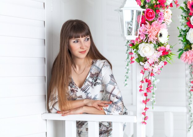 Bella ragazza sotto il portico con lanterna bianca, fiori decorati