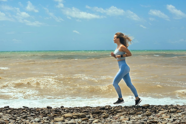 bella ragazza sportiva che pareggia lungo la riva del mare in una giornata di sole