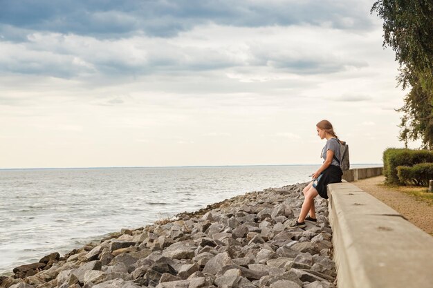 Bella ragazza sul mare con cielo blu e nuvole