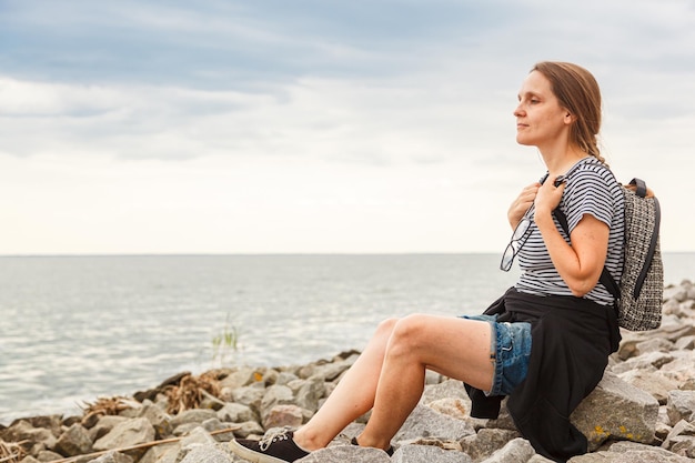 Bella ragazza sul mare con cielo blu e nuvole