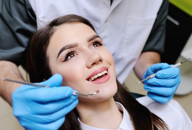 Bella ragazza sulla sedia dentale all'esame dal dentista