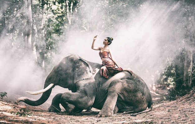 Bella ragazza tailandese donna che indossa abiti cultura nativa trascorrere del tempo con l'elefante nella giungla in campagna, villaggio di elefanti Surin, Thailandia