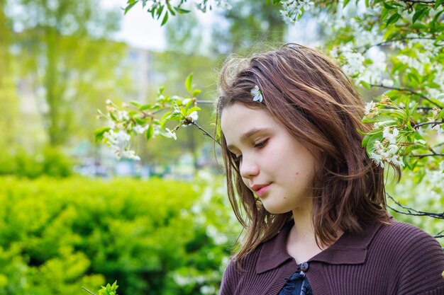 Bella ragazza tra i fiori di ciliegio in primavera Ritratto di una ragazza con i capelli castani e gli occhi verdi