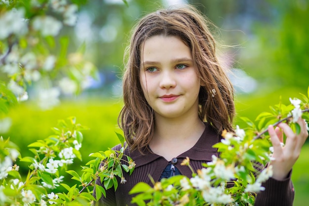 Bella ragazza tra i fiori di ciliegio in primavera Ritratto di una ragazza con i capelli castani e gli occhi verdi