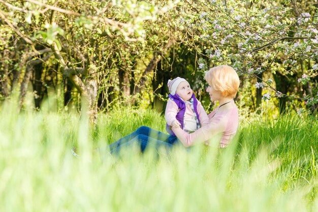 Bella ragazza tra le braccia di una bambina in un parco in fiore