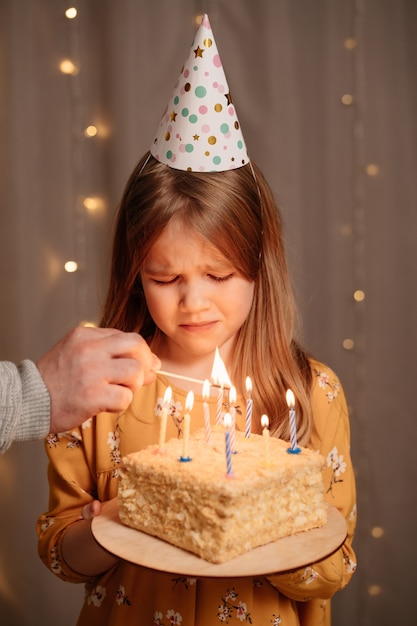 Bella ragazza triste con torta di compleanno.